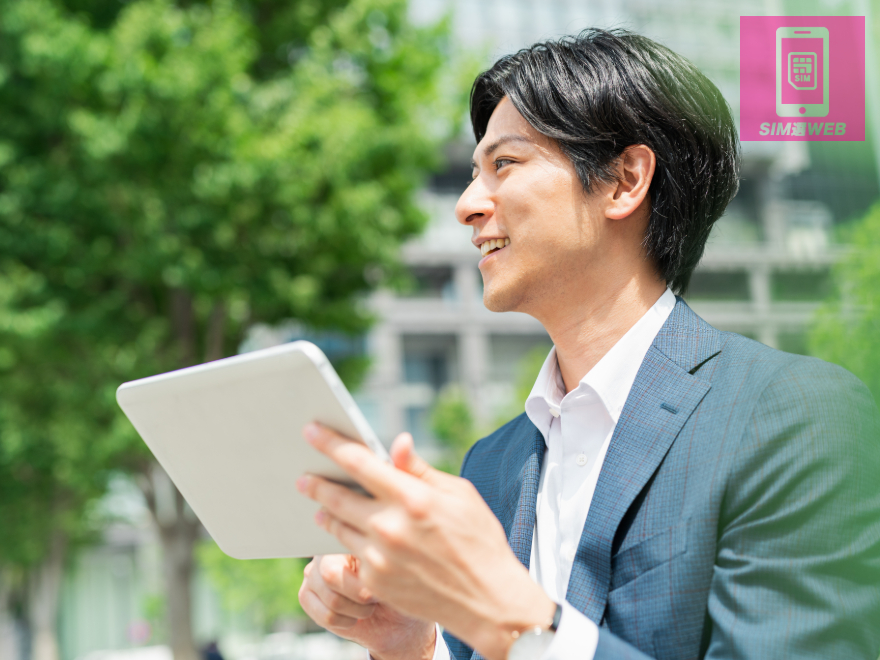 外でタブレットを使う男性
