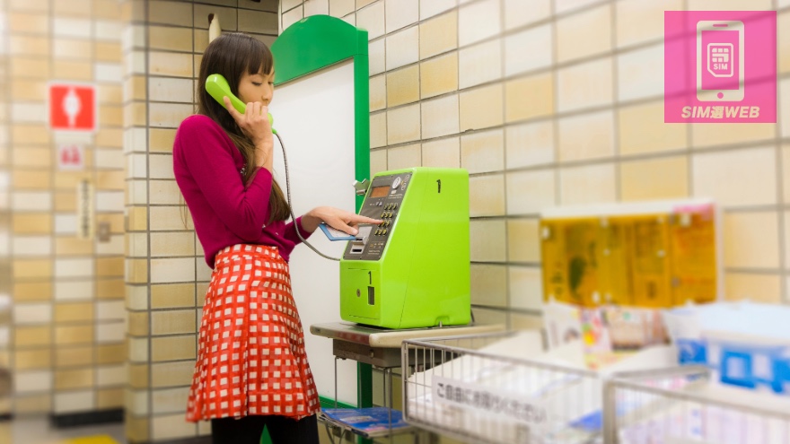 公衆電話を使っている女性