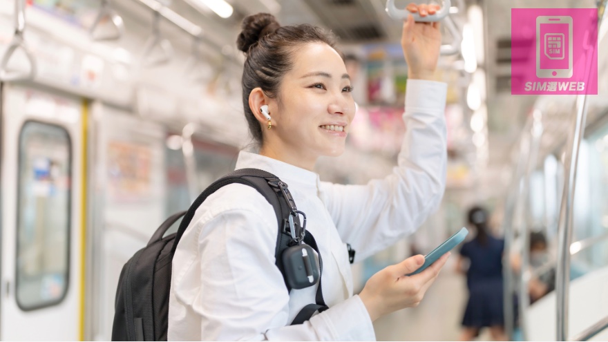 地下鉄でスマホを見る女性